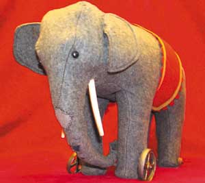 a%20grey%20elephant%20toy%20on%20wheels%20with%20a%20red%20band%20around%20its%20back